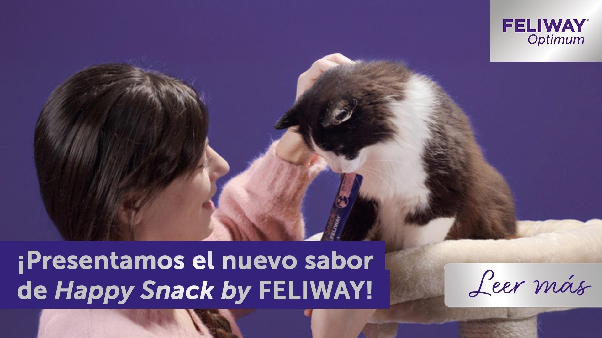 Persona ofreciendo un premio a un gato blanco y negro sentado en un árbol para gatos, con texto promocional de Happy Snack by FELIWAY sobre un fondo morado.
